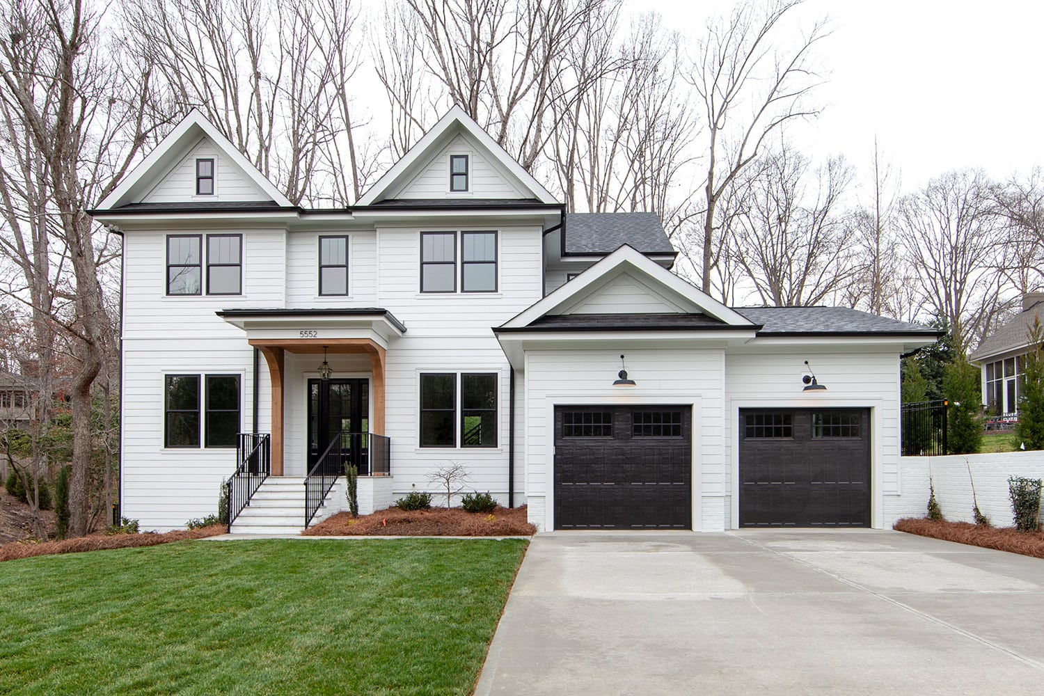 White farmhouse with black windows and garage doors, custom home in Charlotte, NC